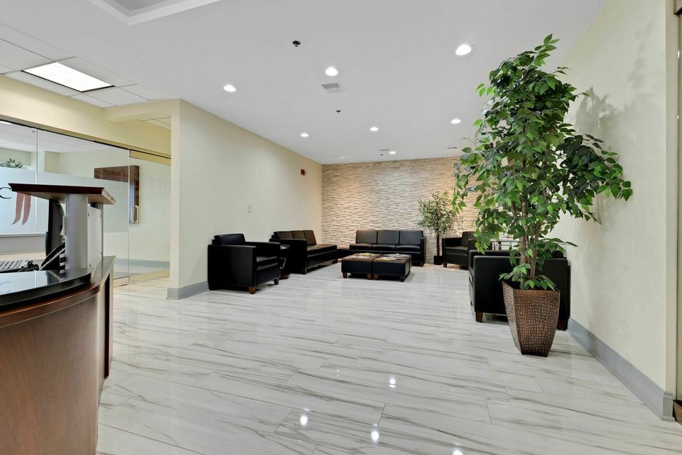 Modern lobby with marble floors, black leather seating, and decorative indoor plants.