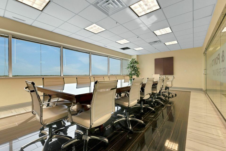 Executive boardroom with long dark table, leather chairs, and floor-to-ceiling windows.