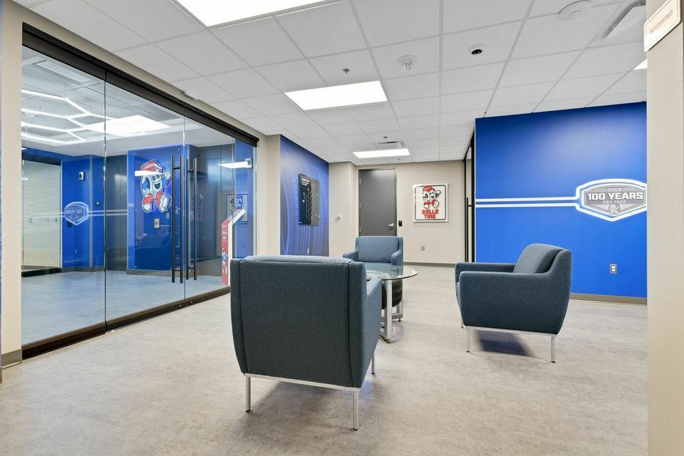 Contemporary office waiting area with blue branding walls and modern gray chairs.