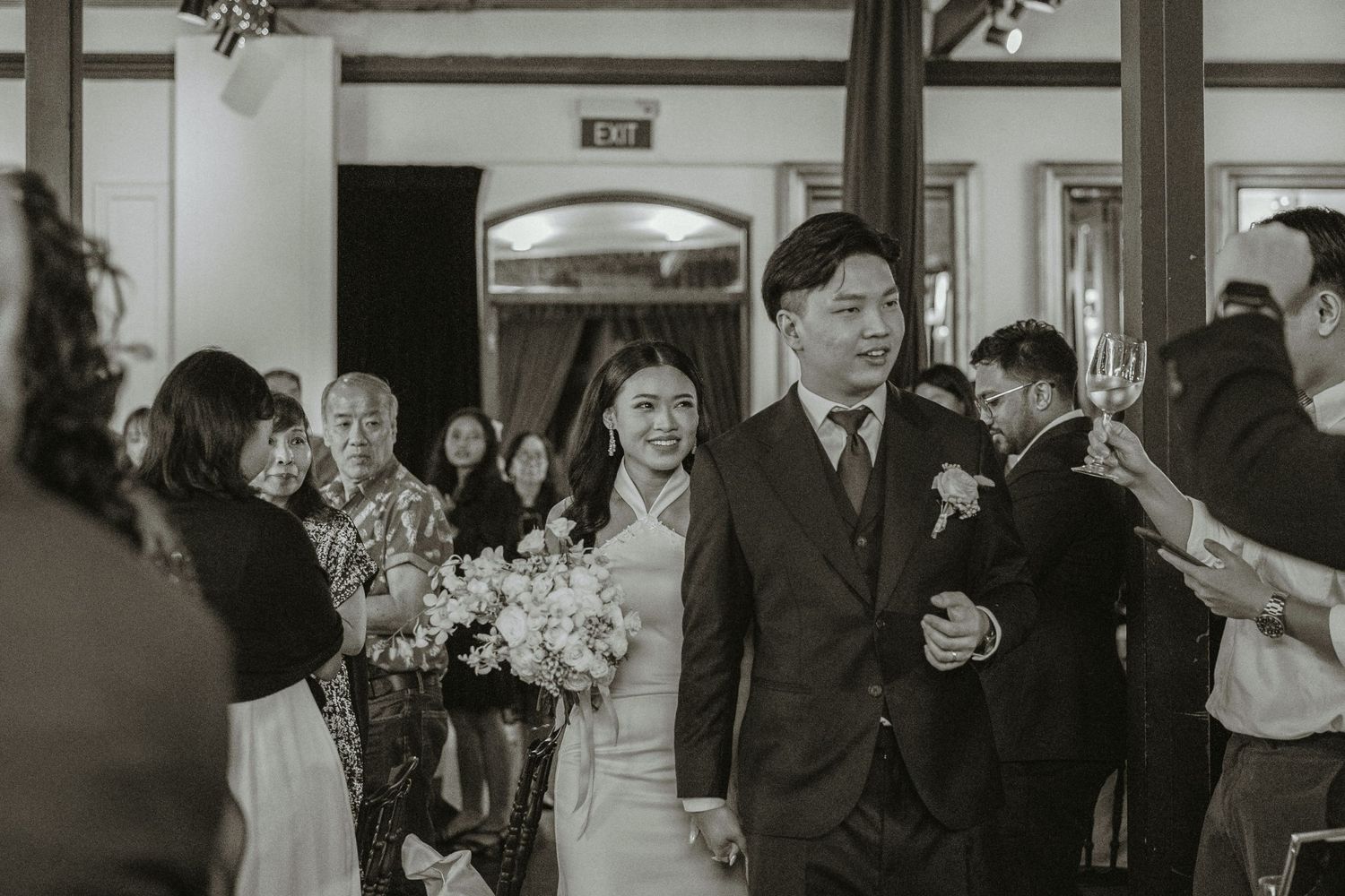 A wedding celebration moment with guests carrying flowers in an indoor venue.