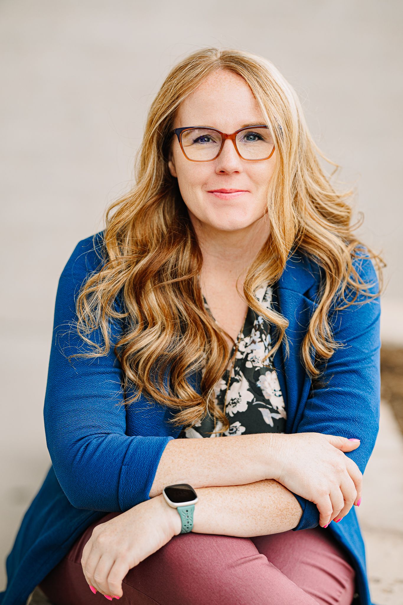 outdoor headshots of women posing in a blue blazer with her hand crossed over.