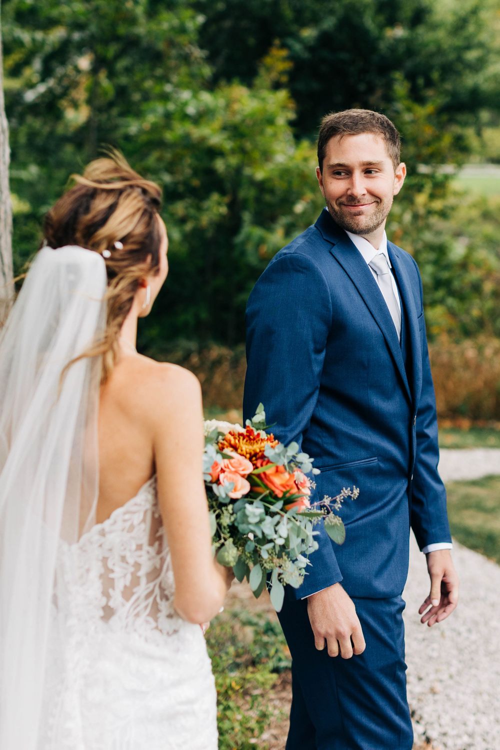 Wedding couple sharing first look moment in outdoor garden setting with colorful autumn bouquet.