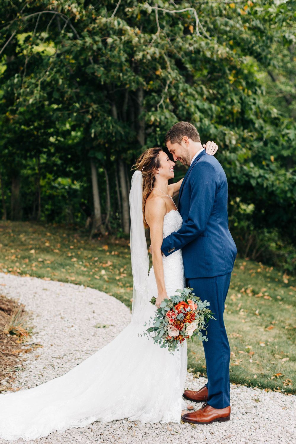 Intimate wedding moment on winding garden path with lush greenery backdrop.