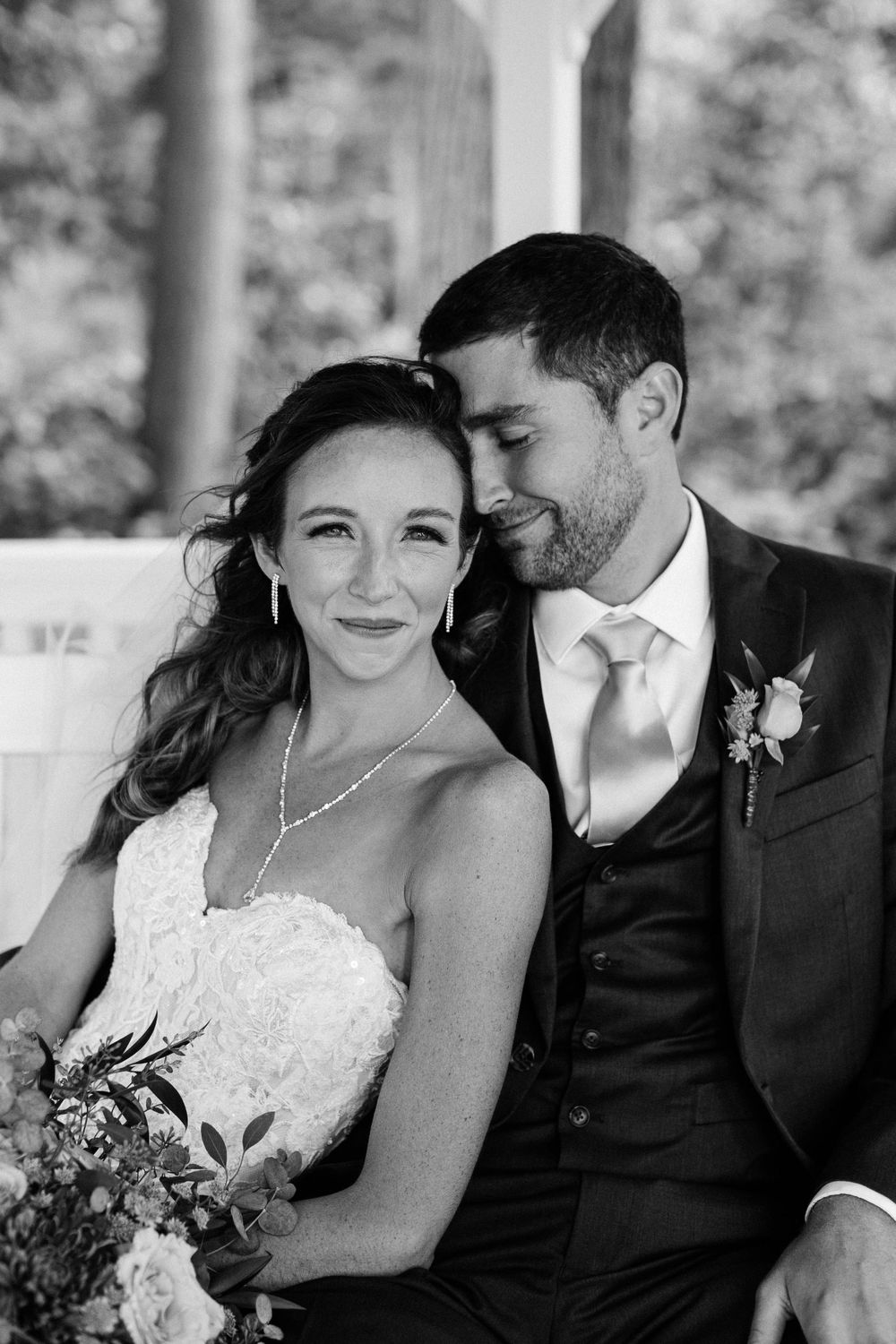 Black and white portrait of newlyweds sharing intimate moment in gazebo.