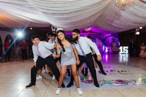 Group of party guests striking dynamic dance poses on illuminated dance floor.