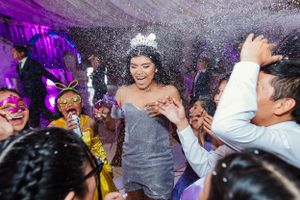 Celebration on dance floor with confetti falling and guests in festive attire dancing.