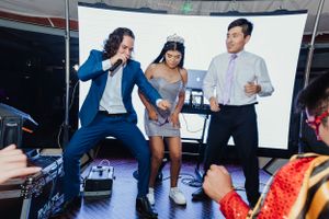 Three people dancing and having fun at a party with a projector screen in the background.