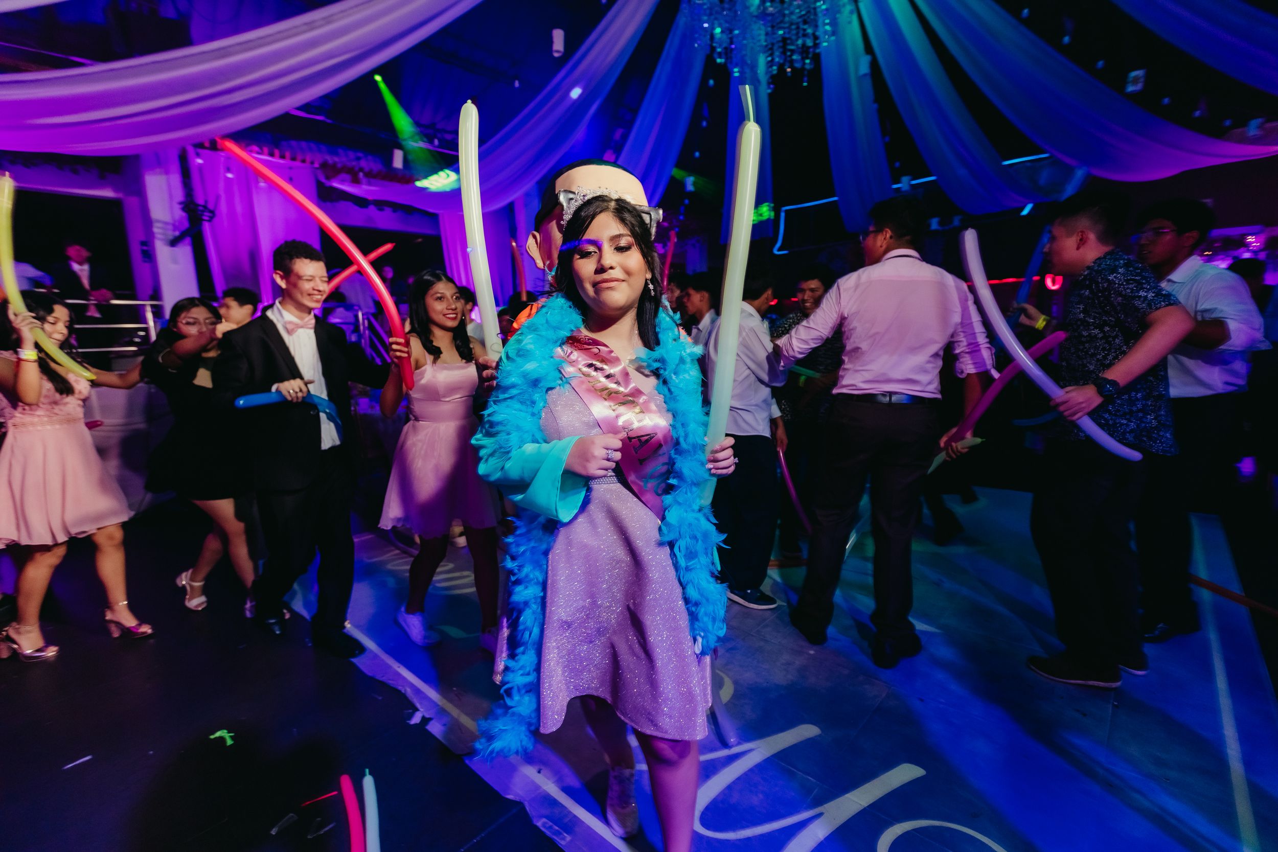 Celebration featuring dancers under blue and purple lighting with draped fabric decor.