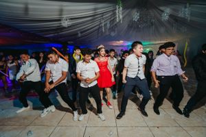A group performs synchronized dance moves at a formal party under dramatic lighting.