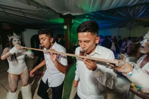 Party guests participate in a limbo game under green and blue lighting at an indoor celebration.