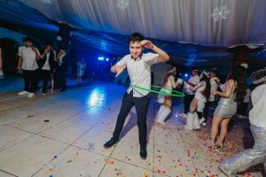 A guest performs a solo dance move on a confetti-covered floor at an indoor celebration.