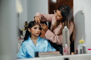 A stylist works on preparing hair in a dressing room setting.