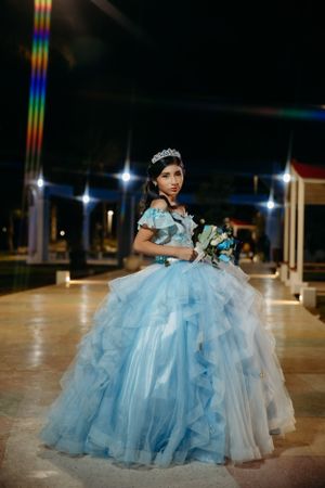 An elegant light blue ball gown photographed at night with dramatic lighting.