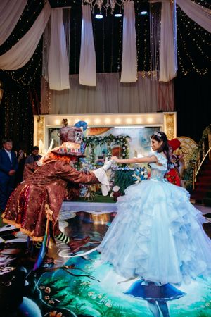 A dramatic scene with a flowing light blue gown against a decorated stage backdrop.
