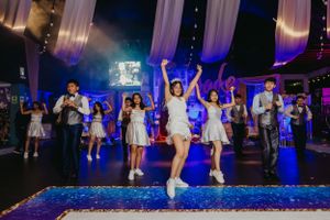 People dancing and celebrating on illuminated blue dance floor at formal event.