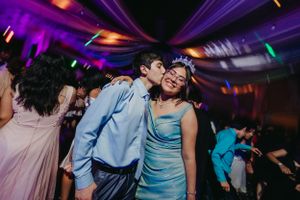 Couples dancing under purple lighting at formal celebration event.