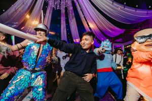 Colorfully dressed dancers perform energetic moves under illuminated fabric decor.