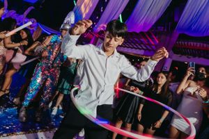 A guest enjoys spinning a hula hoop on the dance floor under dramatic purple lighting.