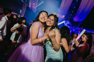 Guests celebrate and embrace on a lively dance floor under purple mood lighting.