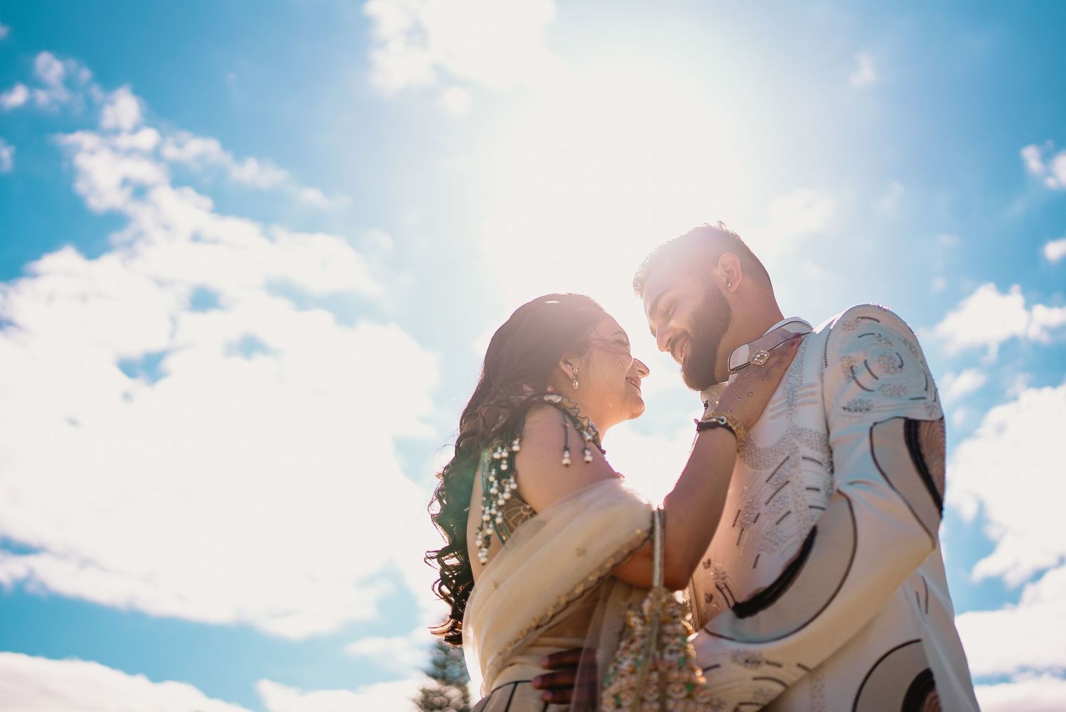 A tender moment between a couple in white clothing at sunset.