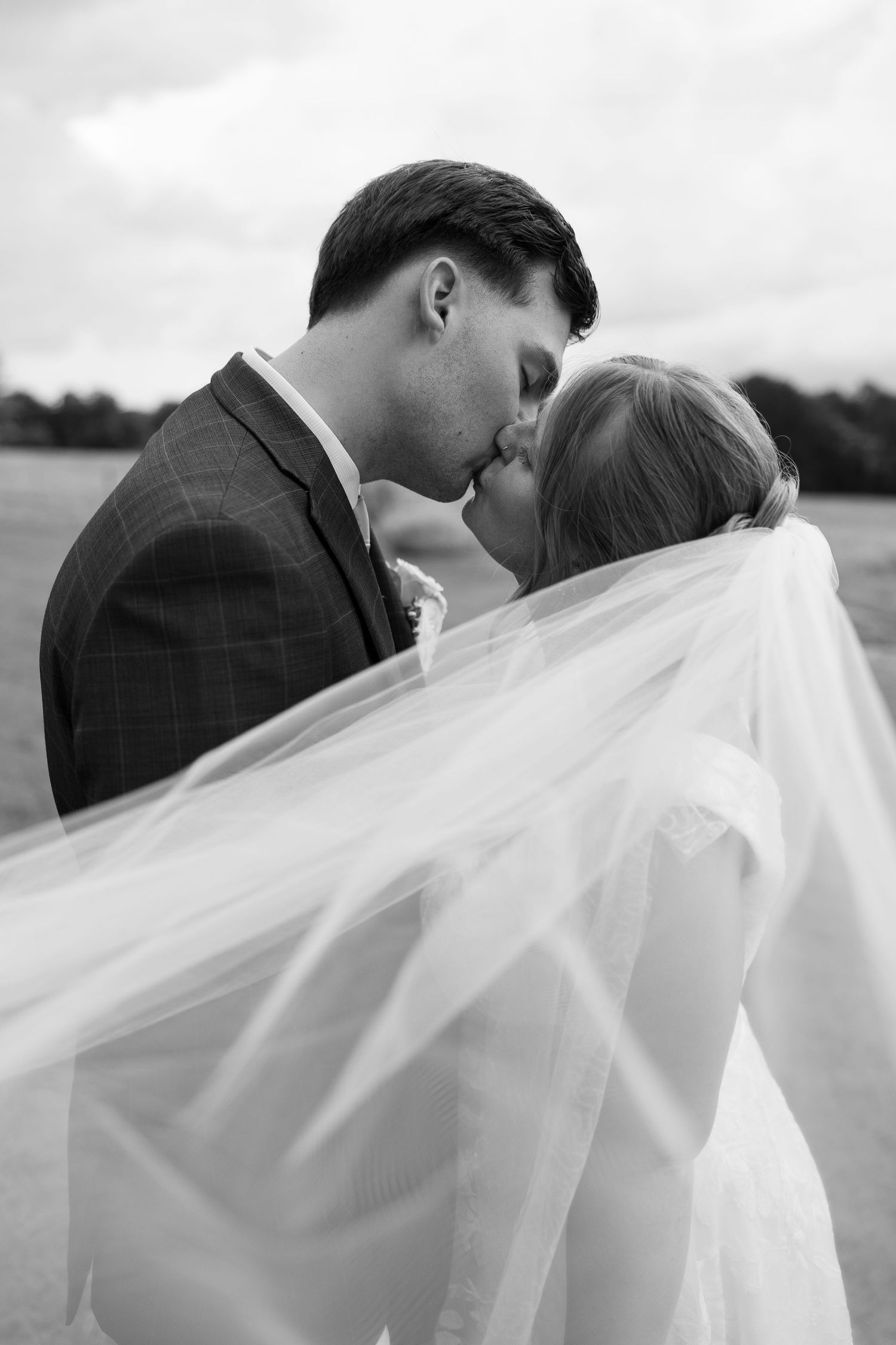 Romantic black and white portrait of couple with flowing wedding veil.