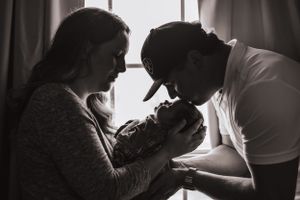 Intimate black and white photo of new parents bonding with their newborn.