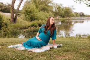 Couple relaxes on blanket by scenic lakeside during outdoor photo session.