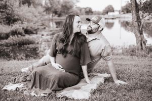 Black and white portrait of couple lounging on grass with their dog.