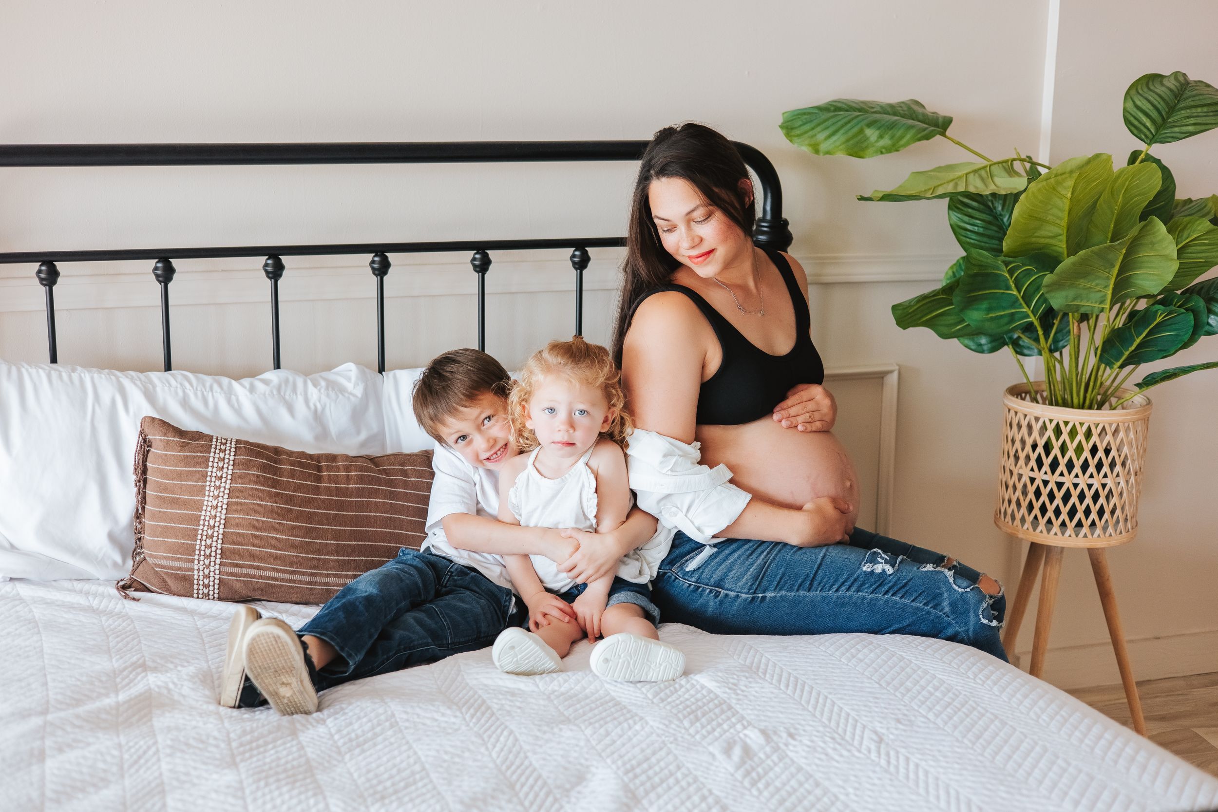 Family relaxes together on white bedding during casual lifestyle photo session.