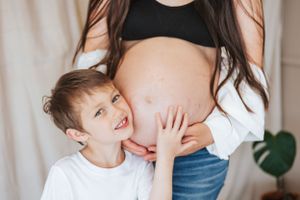 Mother and child share intimate bonding moments in a bright indoor setting with white backdrop.