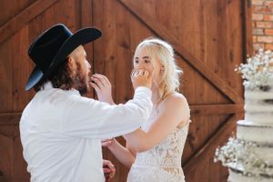 Romantic moments captured between newlyweds in front of a rustic wooden barn door.