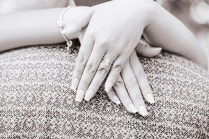 Close-up of hands resting on textured gray carpet.