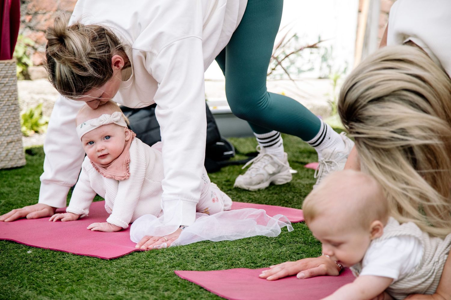 A group exercises together on yoga mats with a baby joining the fitness session.