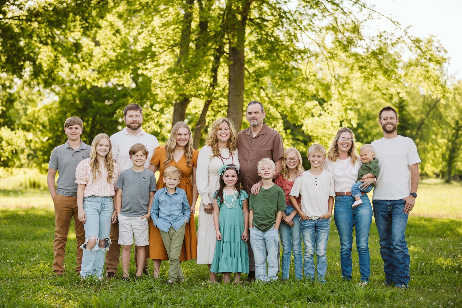 family session with lots of children and grandparents and parents standing in green grass