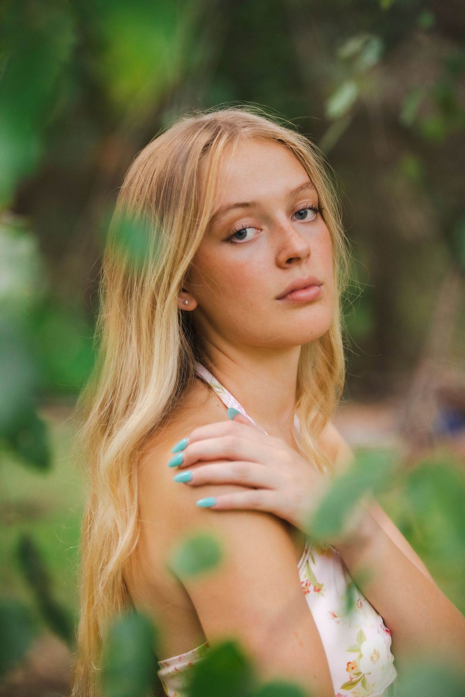 leaves surrounding senior session of girl with blonde hair in white dress