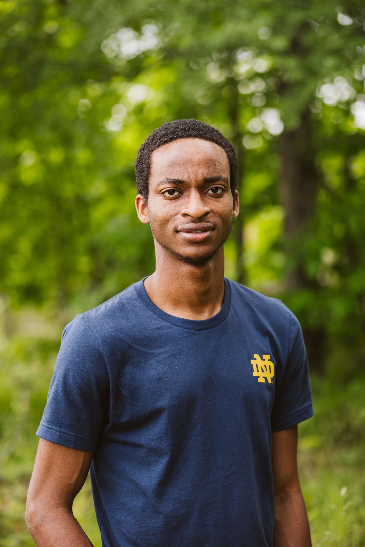 male student wearing t-shirt and standing in forest