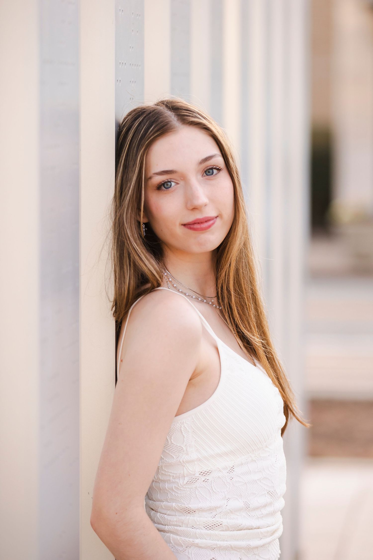 senior girl in white shirt leaning against wall