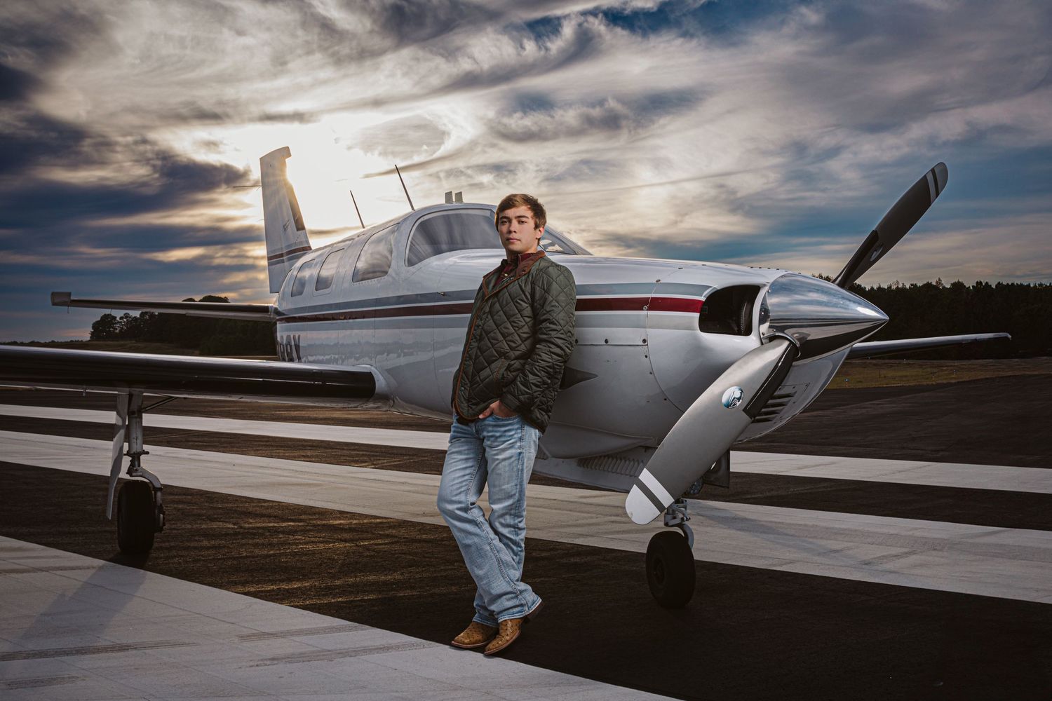 male student leaning against airplane for senior session