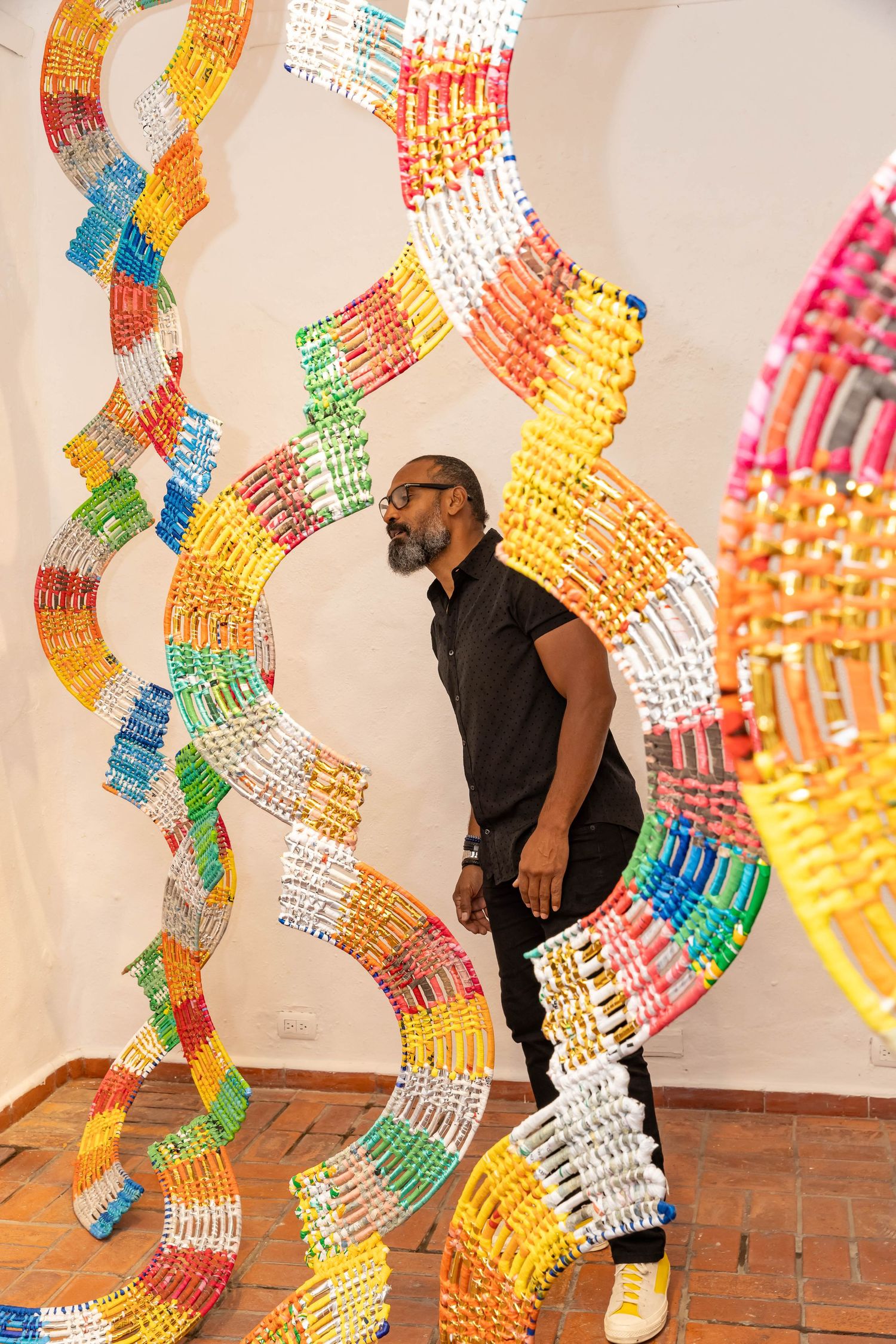 Colorful plastic chain art installation with rainbow-colored segments in curved patterns.
