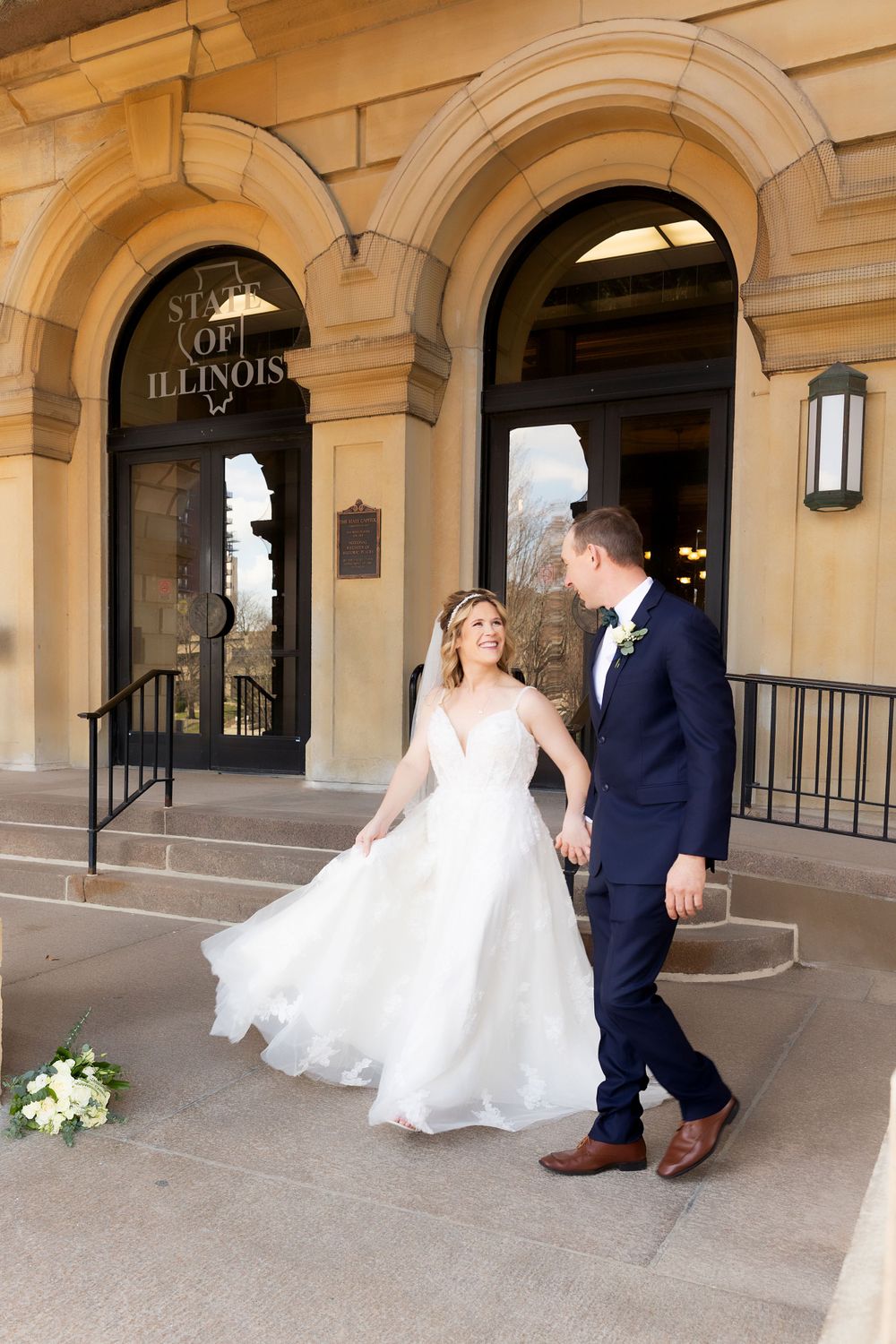 Newlyweds exiting a building with beautiful archways and columns.