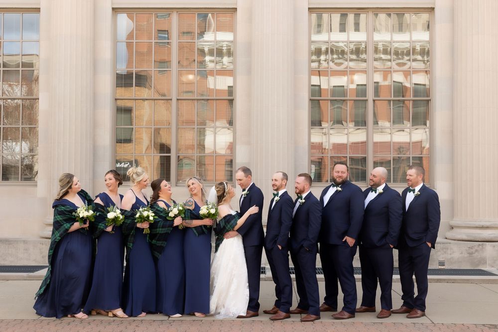 Wedding party in navy blue and white poses in front of a historic building.