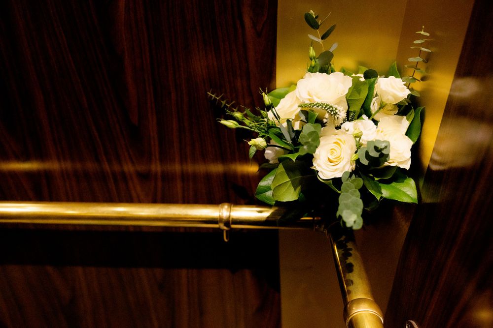 White rose wedding bouquet arrangement against dark wood paneling in warm lighting.