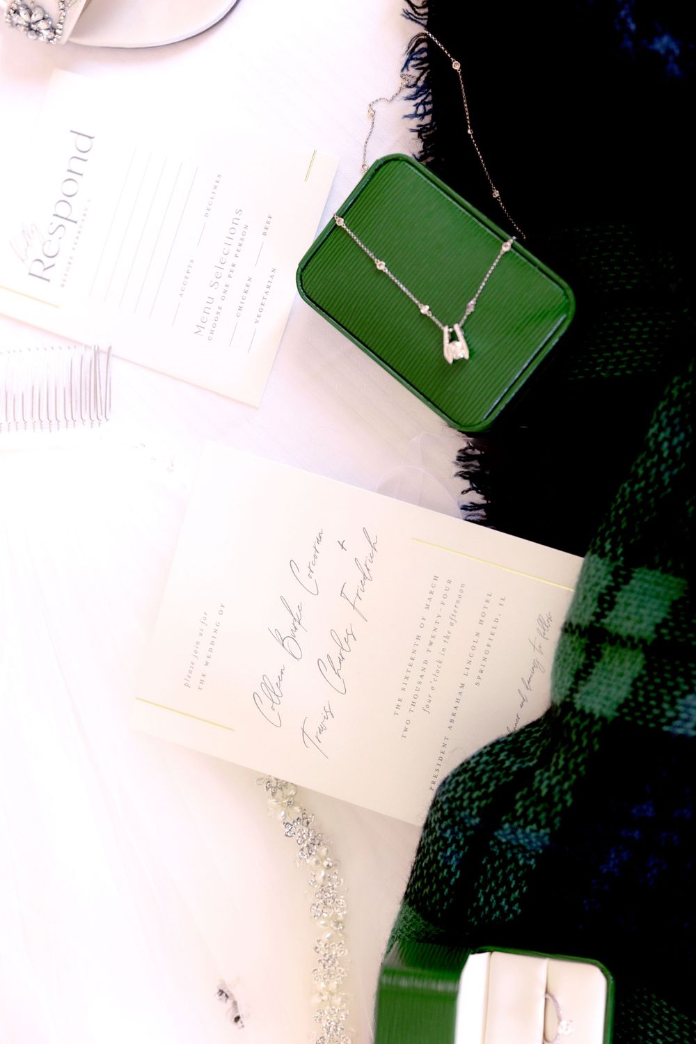 Green velvet jewelry box with necklace displayed on white paper with dark fabric in background.