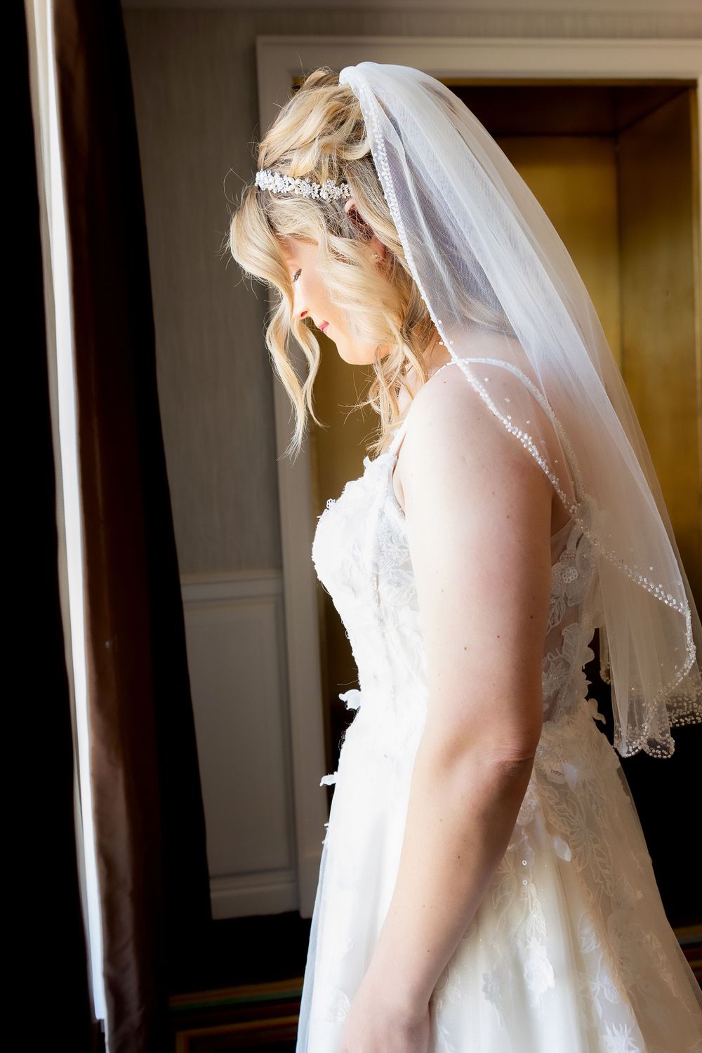 A white wedding dress with delicate veil and lace details in soft lighting.