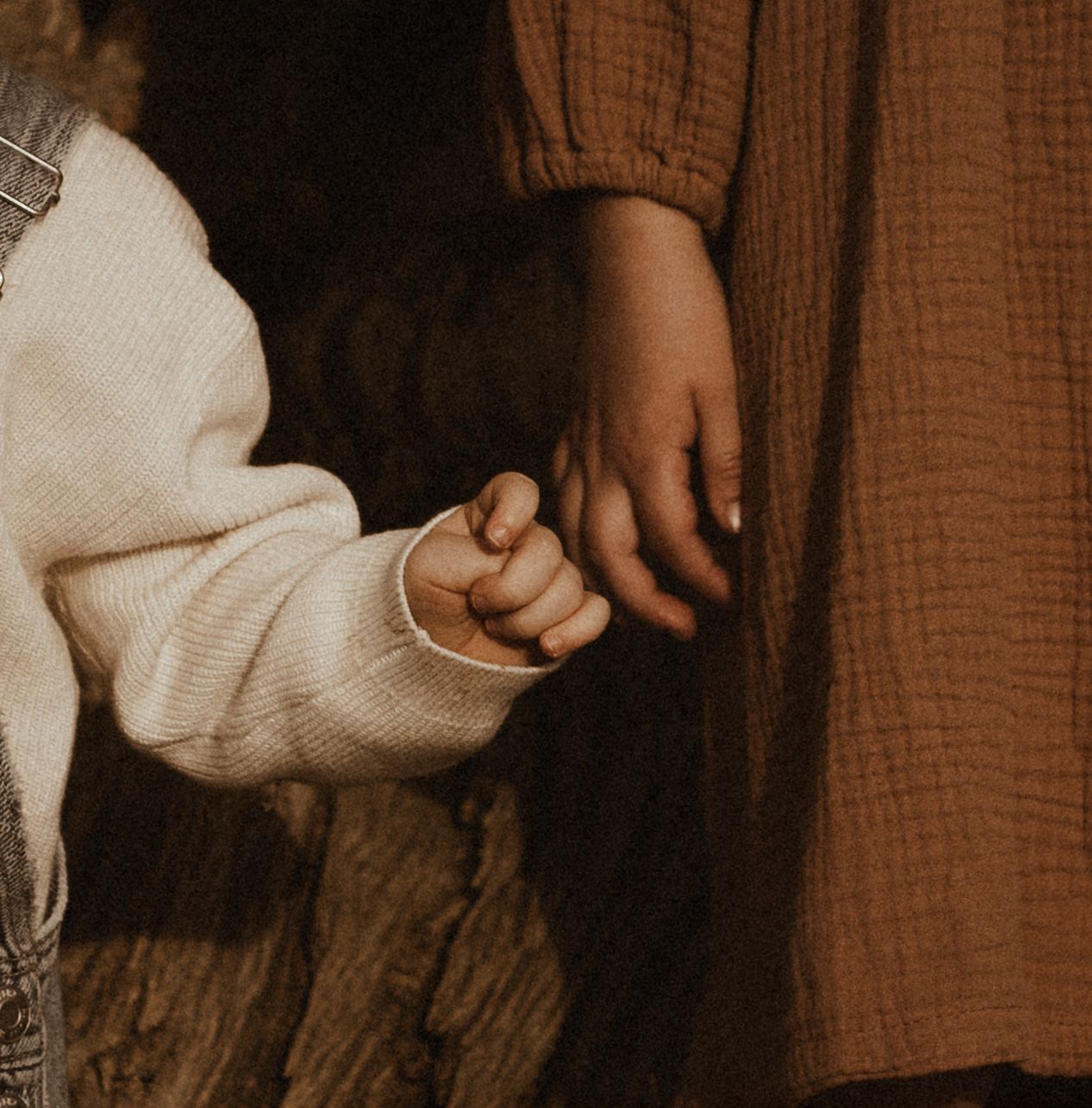 A close-up view of hands holding each other in Javea  in warm brown and cream tones. Javea family photographer