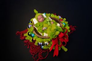 Time lapse sequence showing a green and red floral Christmas ornament arrangement being assembled against a dark background.