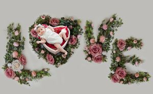 Love spelled with floral arrangements and heart-shaped nest containing newborn.