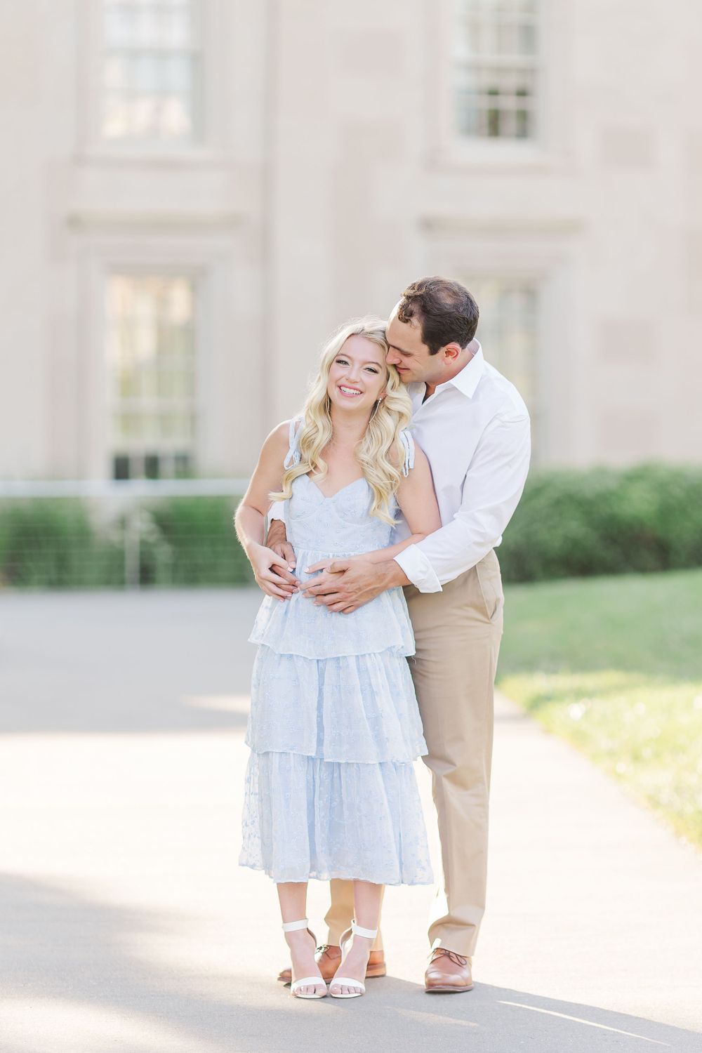 A couple shares a tender moment in matching white and blue outfits during their engagement session.