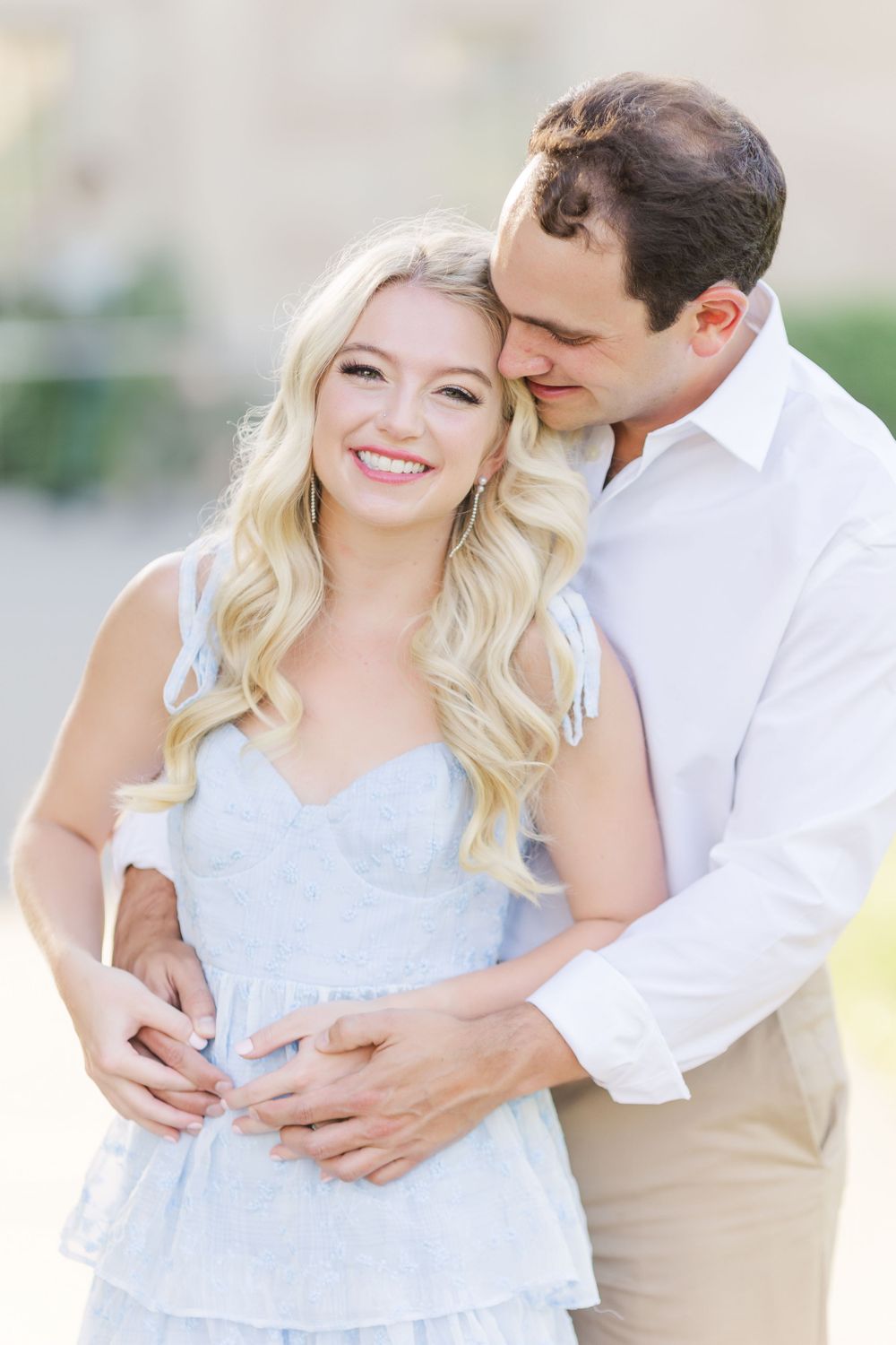 A romantic embrace captured in soft light with the couple wearing coordinated pastel outfits.