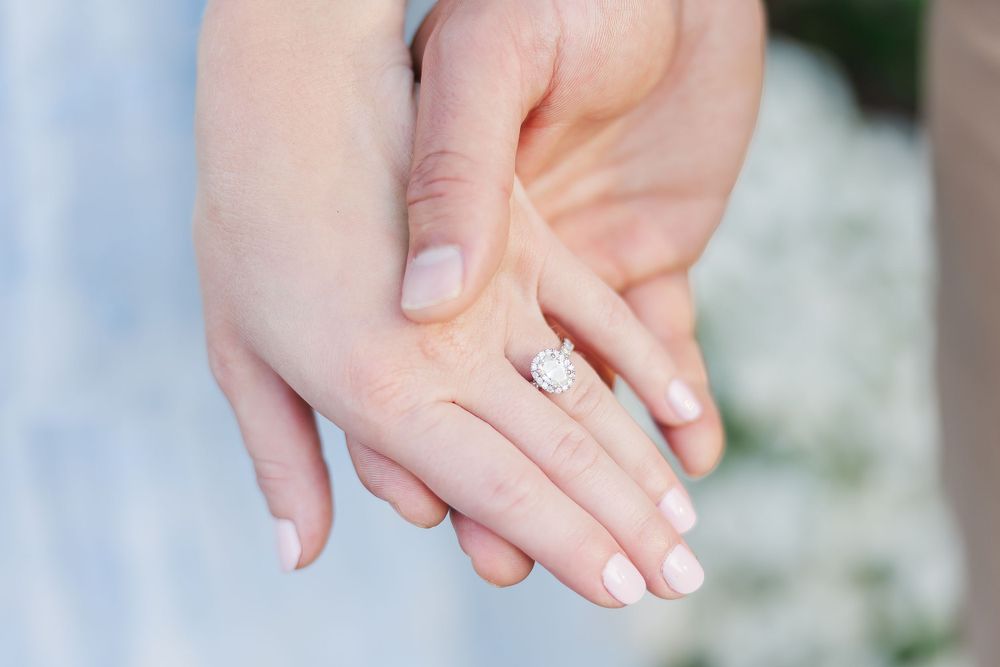Close-up of hands showing off an engagement ring in natural light.